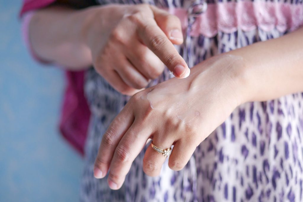 pexels photo 11030161 A woman applies skincare cream on her hand, highlighting moisturizing routine.