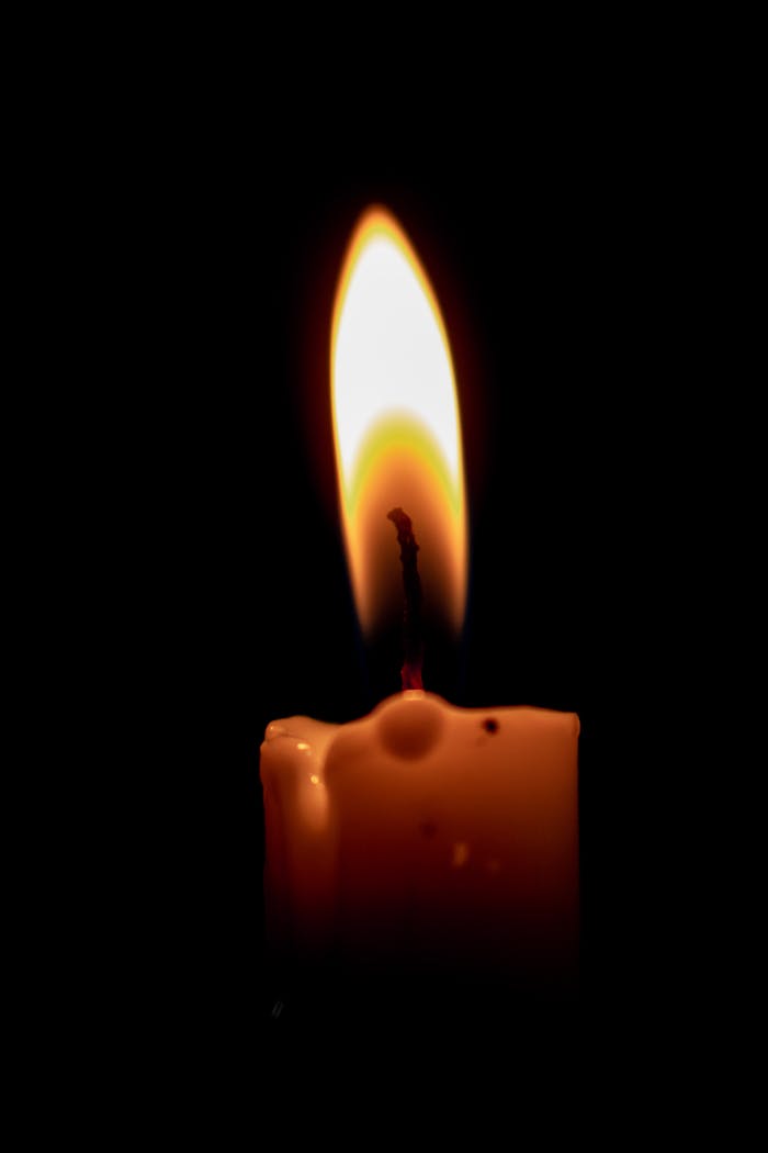 services-img A burning candle casting a warm glow in the dark, highlighting serenity and calmness.